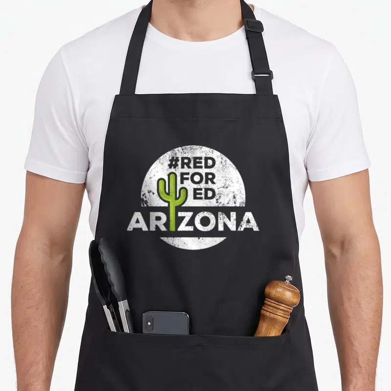 Arizona teacher apron - Green cactus inside distressed white circle with #RED FOR ED and ARIZONA text — shown on a black cotton canvas apron against a white background