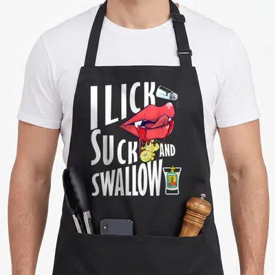 Tequila st patrick day aprons - Red lips licking salt and lime with I LICK SUCK AND SWALLOW text and tequila shot glass — shown on a black cotton canvas apron against a white background