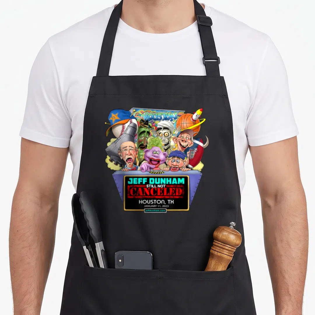 Houston hollywood apron - Jeff Dunham Still Not Canceled cartoon puppets and sports equipment above blue and black sign — shown on a black cotton canvas apron against a white background