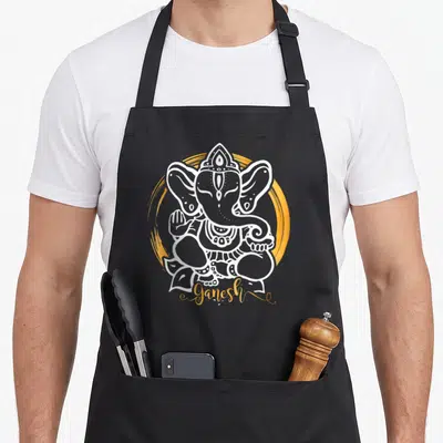 Hindu funny diwali apron - White line-art Ganesha inside gold brushstroke with Ganesh script below — shown on a black cotton canvas apron against a white background