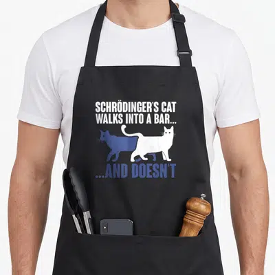 Humour cat apron - Schrödinger's Cat pun text with overlapping blue and white cat silhouettes — shown on a black cotton canvas apron against a white background