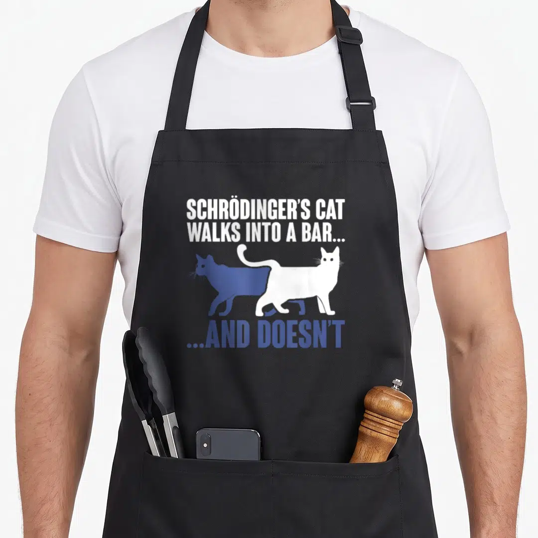Humour cat apron - Schrödinger's Cat pun text with overlapping blue and white cat silhouettes — shown on a black cotton canvas apron against a white background