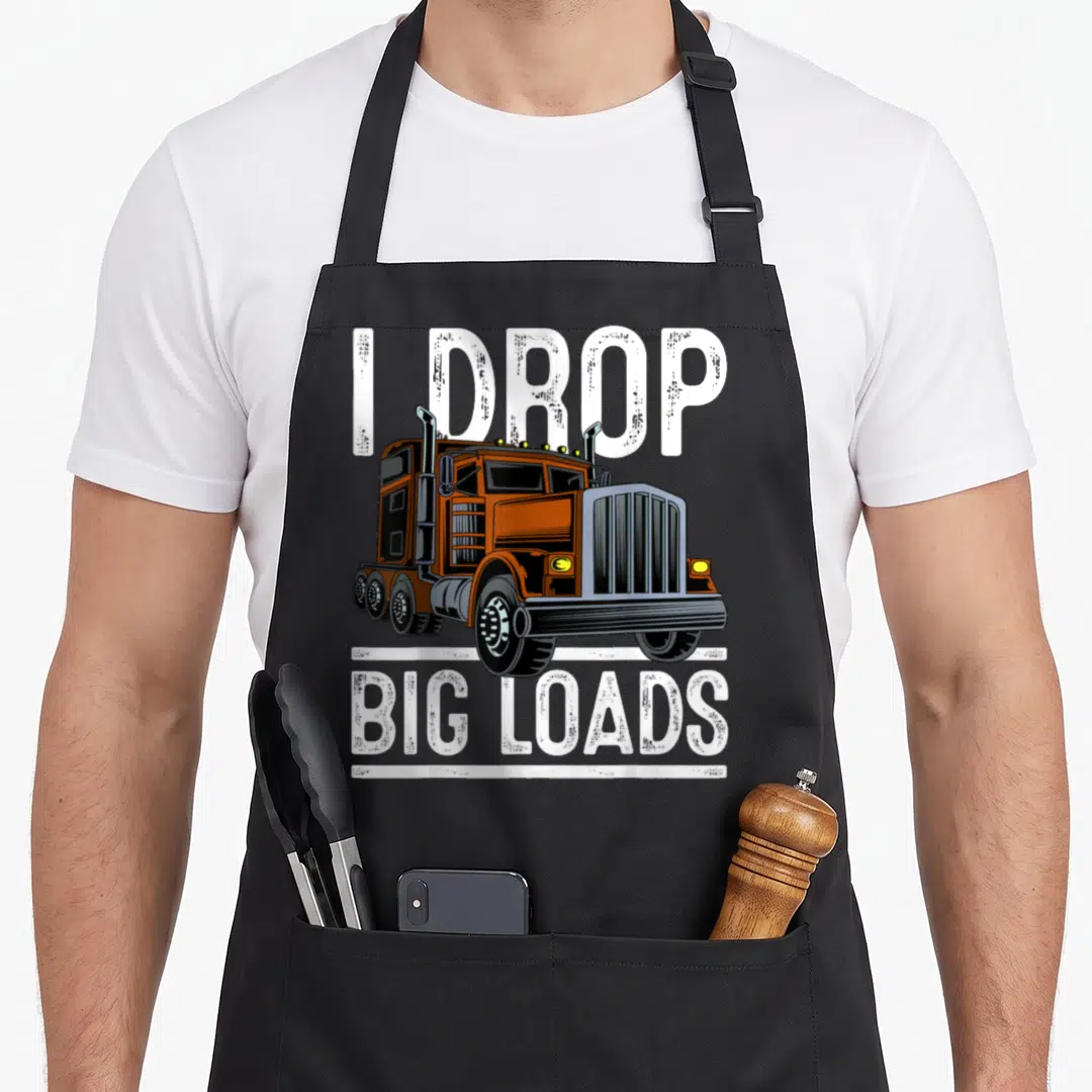 Cute truck apron - Orange semi-truck with I DROP BIG LOADS text in white and black — shown on a black cotton canvas apron against a white background