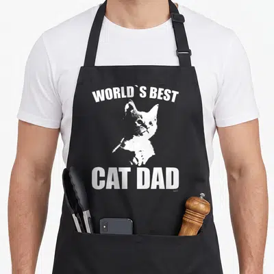 Vintage kitten cat apron - White cat illustration between arched and straight text reading WORLD'S BEST CAT DAD — shown on a black cotton canvas apron against a white background