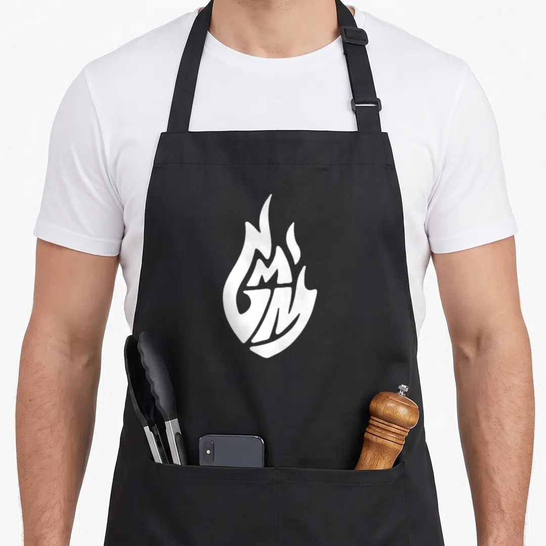 Retro good mythical morning apron - White flame shape containing stylized GM letters on a grey background — shown on a black cotton canvas apron against a white background