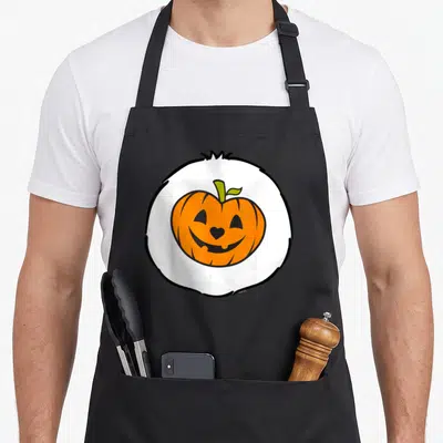 Trick sweet halloween apron - Cartoon orange pumpkin with heart nose inside white circle with black outline — shown on a black cotton canvas apron against a white background