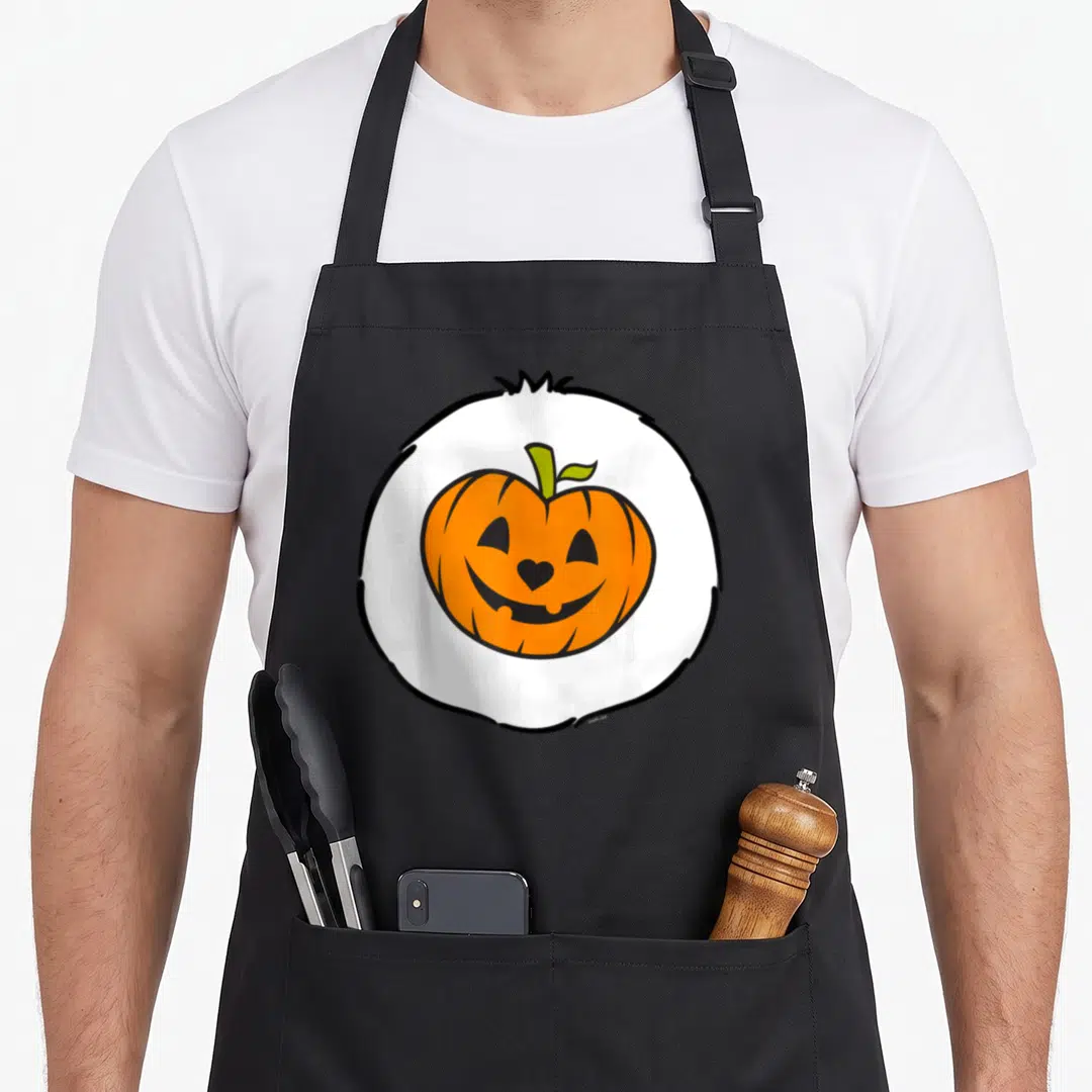 Trick sweet halloween apron - Cartoon orange pumpkin with heart nose inside white circle with black outline — shown on a black cotton canvas apron against a white background