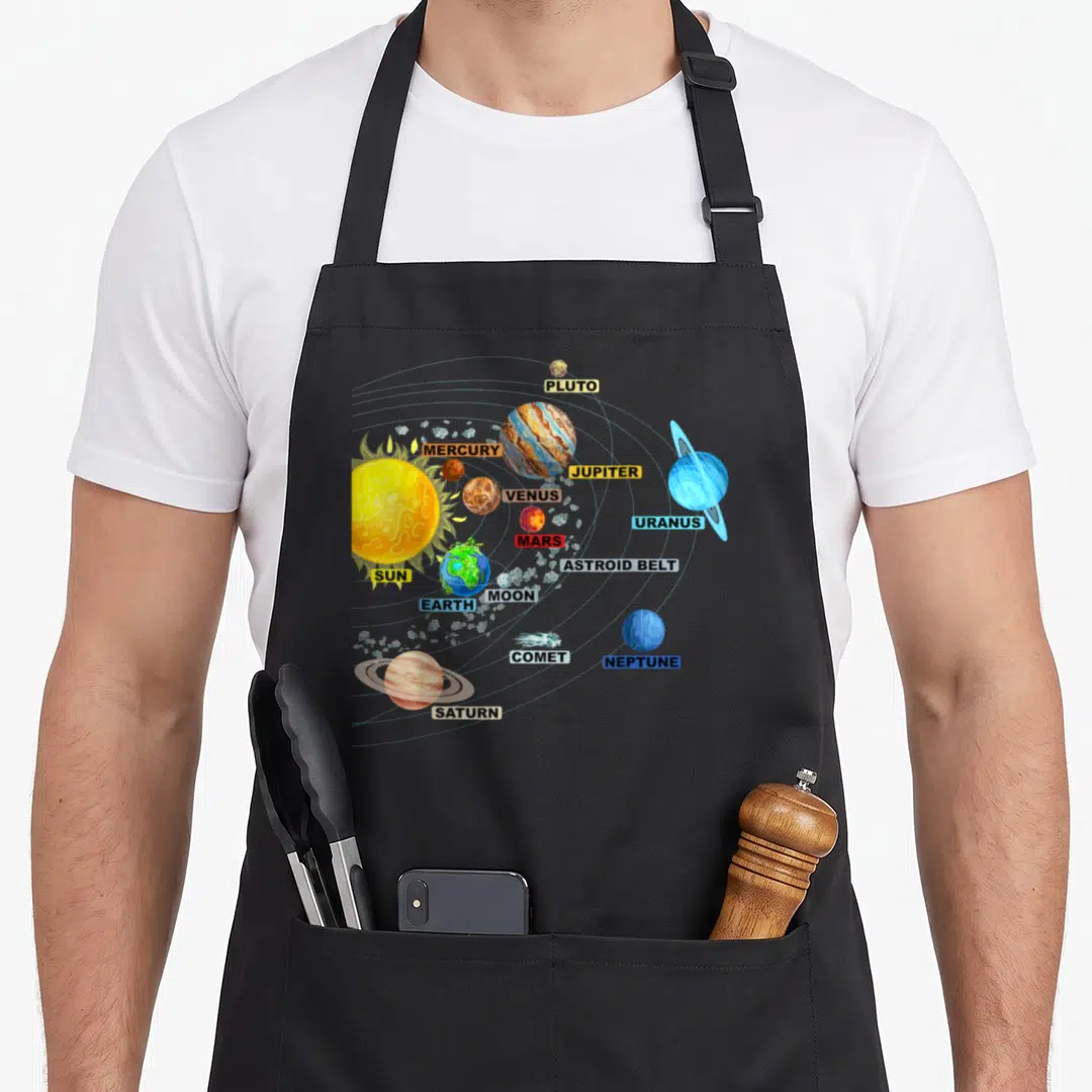 Solar science apron - Cartoon solar system with labeled planets and sun in colored boxes — shown on a black cotton canvas apron against a white background
