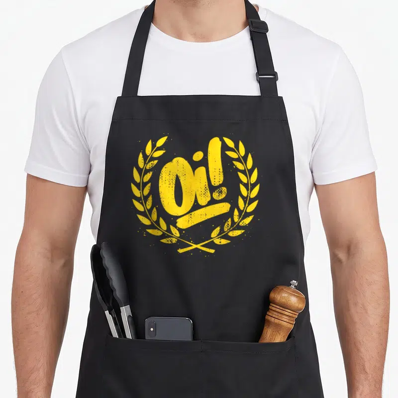 Ska punk rock apron - Distressed yellow Oi! text inside a circular laurel wreath — shown on a black cotton canvas apron against a white background