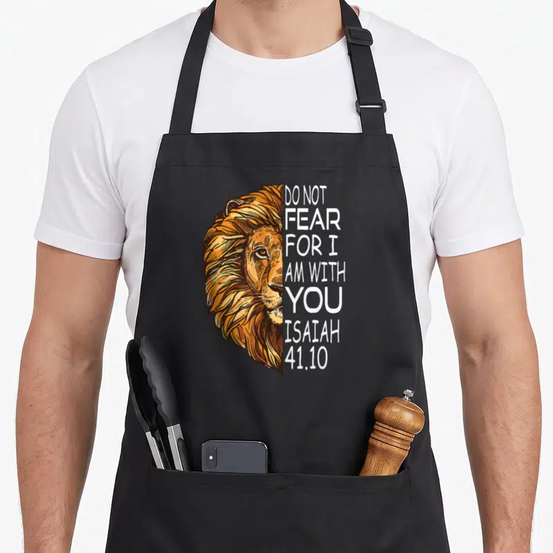 Fear bible verse apron - Realistic lion head illustration next to vertical Do Not Fear For I Am With You Isaiah 41.10 — shown on a black cotton canvas apron against a white background