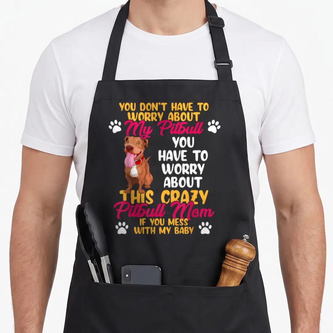 Pitbull mess apron - Cartoon brown pitbull with stacked yellow and pink text and four white paw prints — shown on a black cotton canvas apron against a white background