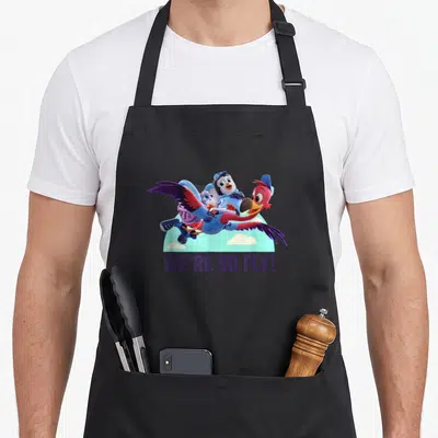 Fly junior apron - Three cartoon birds flying over clouds with We're So Fly text — shown on a black cotton canvas apron against a white background