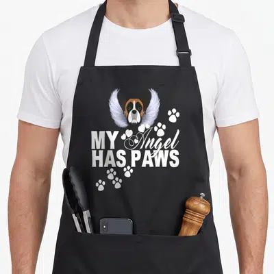 Angel boxer dog apron - Winged boxer head with MY Angel HAS PAWS text and paw prints — shown on a black cotton canvas apron against a white background