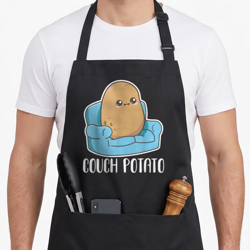 Couch kawaii apron - Cartoon brown potato in blue armchair with white COUCH POTATO text — shown on a black cotton canvas apron against a white background