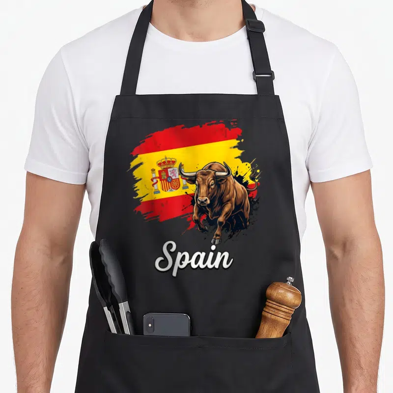 National spanish aprons - Realistic brown bull on red yellow brush stroke flag with white Spain script text — shown on a black cotton canvas apron against a white background