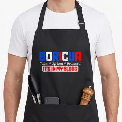 Boricua spanish aprons - Distressed BORICUA text in blue white red with Taino African Spaniard script and two small — shown on a black cotton canvas apron against a white background