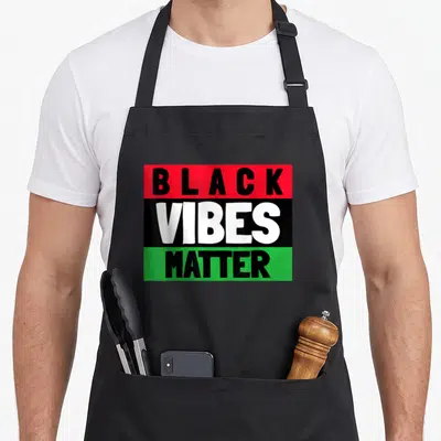 Matter black apron - Stacked BLACK VIBES MATTER text on red, black, and green horizontal stripes — shown on a black cotton canvas apron against a white background