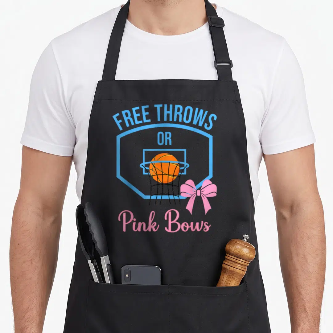 Free bow apron - Free Throws or Pink Bows basketball shield with orange ball and pink bow — shown on a black cotton canvas apron against a white background