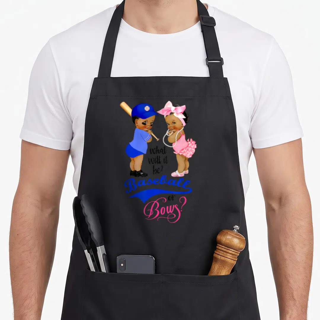 Ethnic bow apron - Two cartoon babies in blue and pink with text what will it be baseball or bows — shown on a black cotton canvas apron against a white background