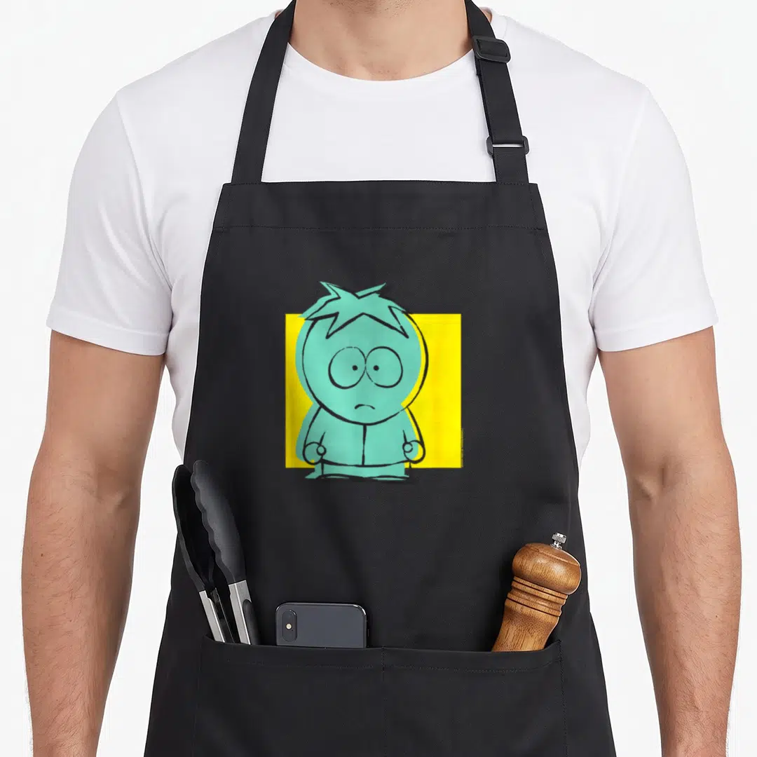Cute butter apron - Teal cartoon character standing in front of a yellow square block — shown on a black cotton canvas apron against a white background