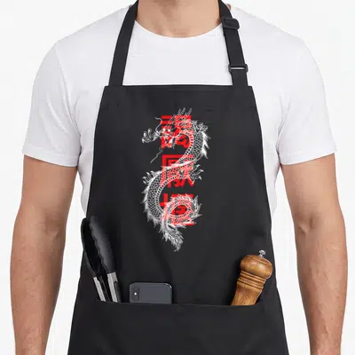 Writing dragon apron - White line-art dragon layered over large red kanji characters — shown on a black cotton canvas apron against a white background