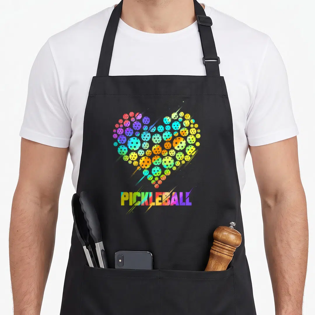Pickleball colorful aprons - Rainbow heart of pickleballs above PICKLEBALL text — shown on a black cotton canvas apron against a white background