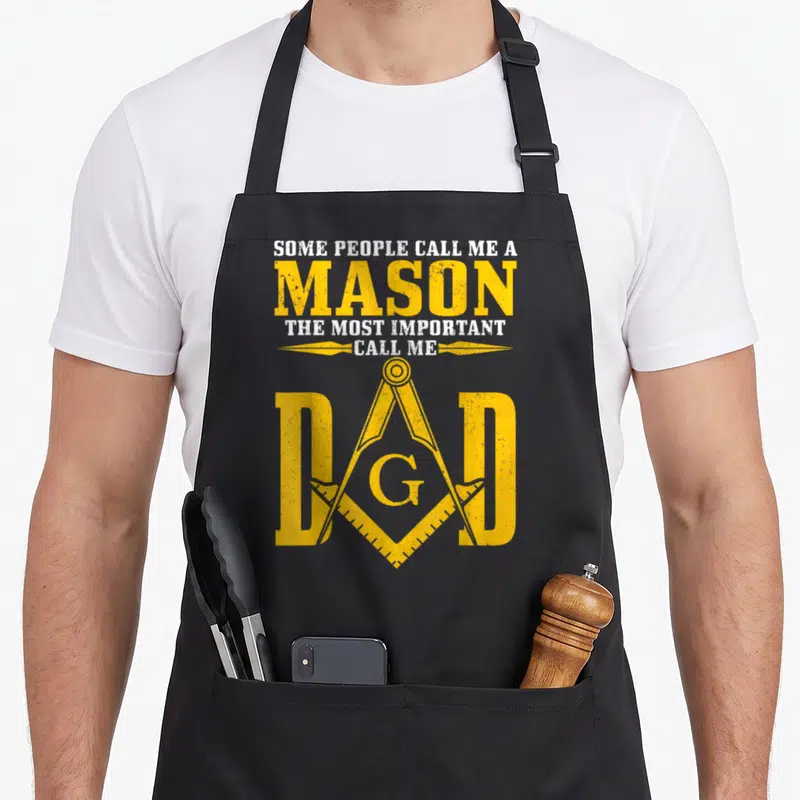Square compass mason apron - Yellow distressed text and masonry symbol overlapping the word DAD on black fabric — shown on a black cotton canvas apron against a white background