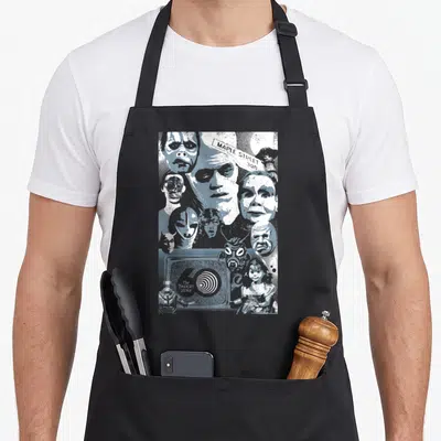 Zone dusk apron - Blue-grey collage of faces, MAPLE STREET sign, TV, doll, astronaut — shown on a black cotton canvas apron against a white background