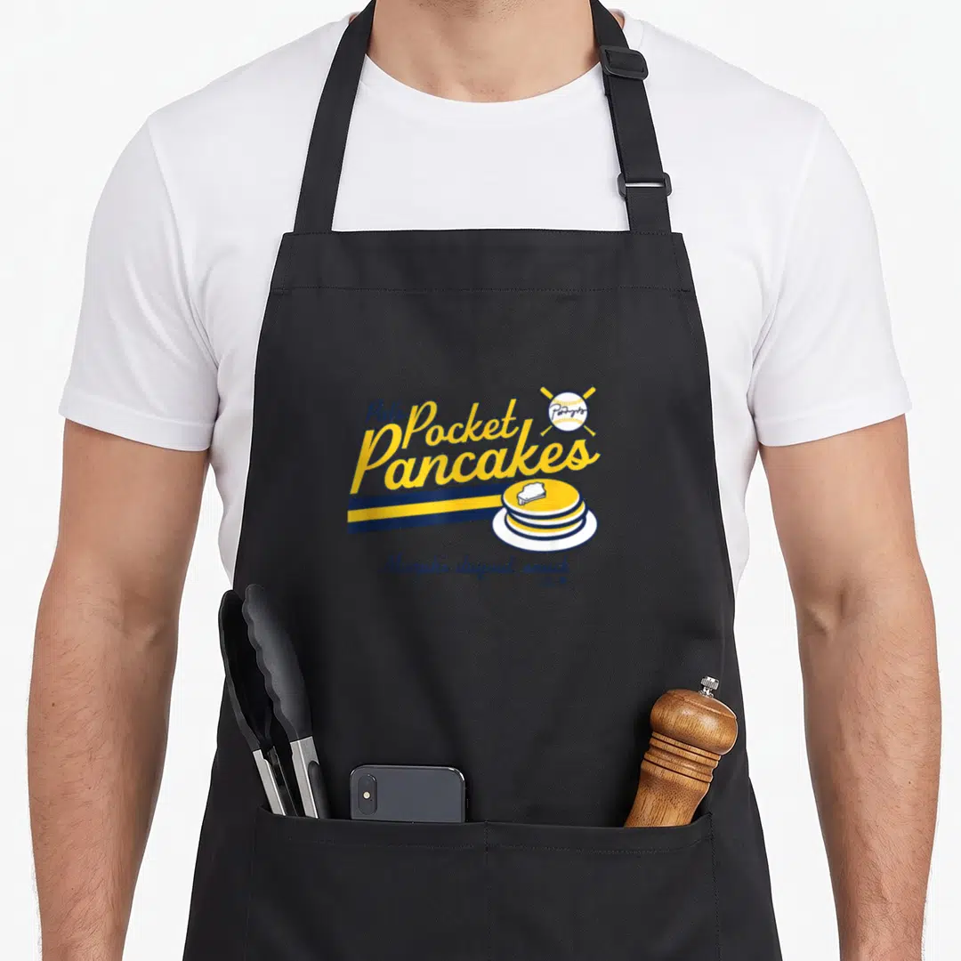 Pat milwaukee apron - Yellow and navy typography reading Pat's Pocket Pancakes above a stack of pancakes and a crossed — shown on a black cotton canvas apron against a white background