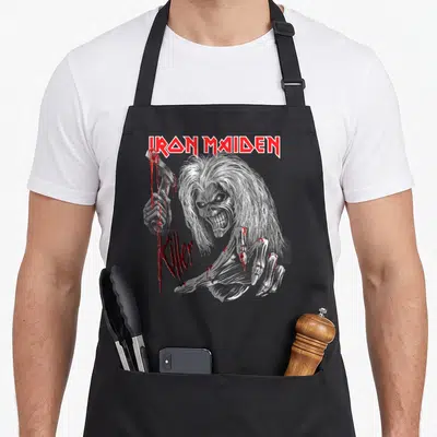 Legacy collection apron - Realistic zombie holding bloody knife with IRON MAIDEN and Killer text in red and grey — shown on a black cotton canvas apron against a white background