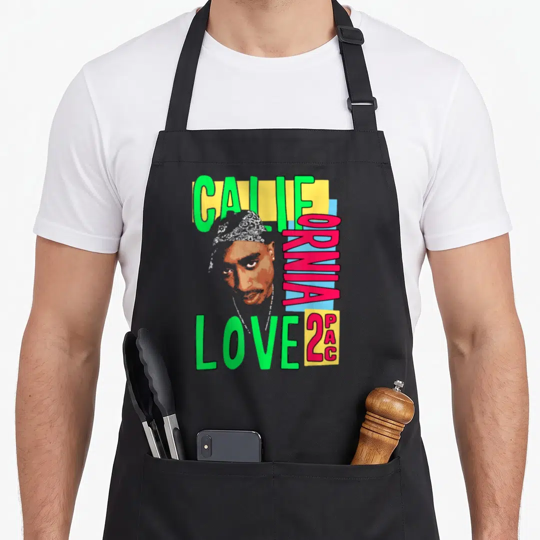 Funny california tupac apron - Tupac portrait with vertical CALIFORNIA LOVE 2PAC text in green pink yellow blue — shown on a black cotton canvas apron against a white background