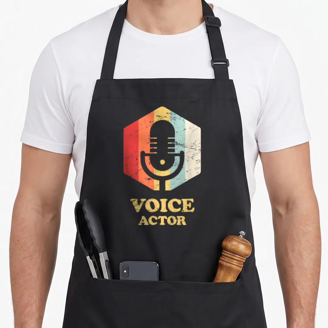 Artist voice acting apron - Retro microphone in striped hexagon with stacked yellow VOICE ACTOR text below — shown on a black cotton canvas apron against a white background