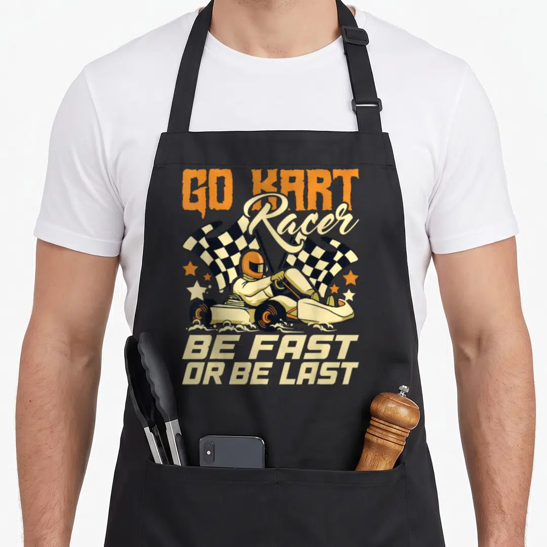 Kart apron or apron - Cartoon go kart racer with two checkered flags and text GO KART Racer BE FAST OR BE LAST — shown on a black cotton canvas apron against a white background