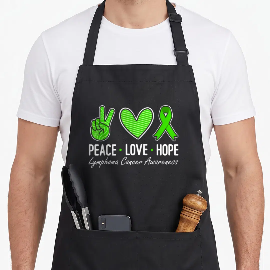 Hope ribbon apron - Green peace hand, striped heart, and ribbon with white text PEACE LOVE HOPE Lymphoma Cancer — shown on a black cotton canvas apron against a white background