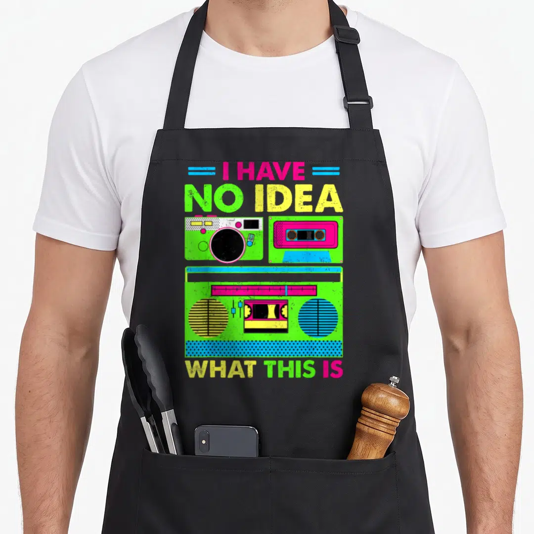 Funny 80s chef outfit with apron - Neon green pink and yellow boombox graphic with text I HAVE NO IDEA WHAT THIS IS — shown on a black cotton canvas apron against a white background