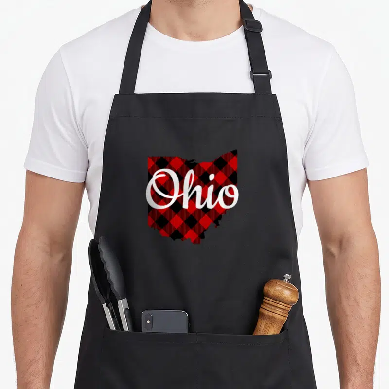 Ohio buffalo plaid apron - Map of Ohio filled with red and black plaid pattern overlaid with white script text reading — shown on a black cotton canvas apron against a white background