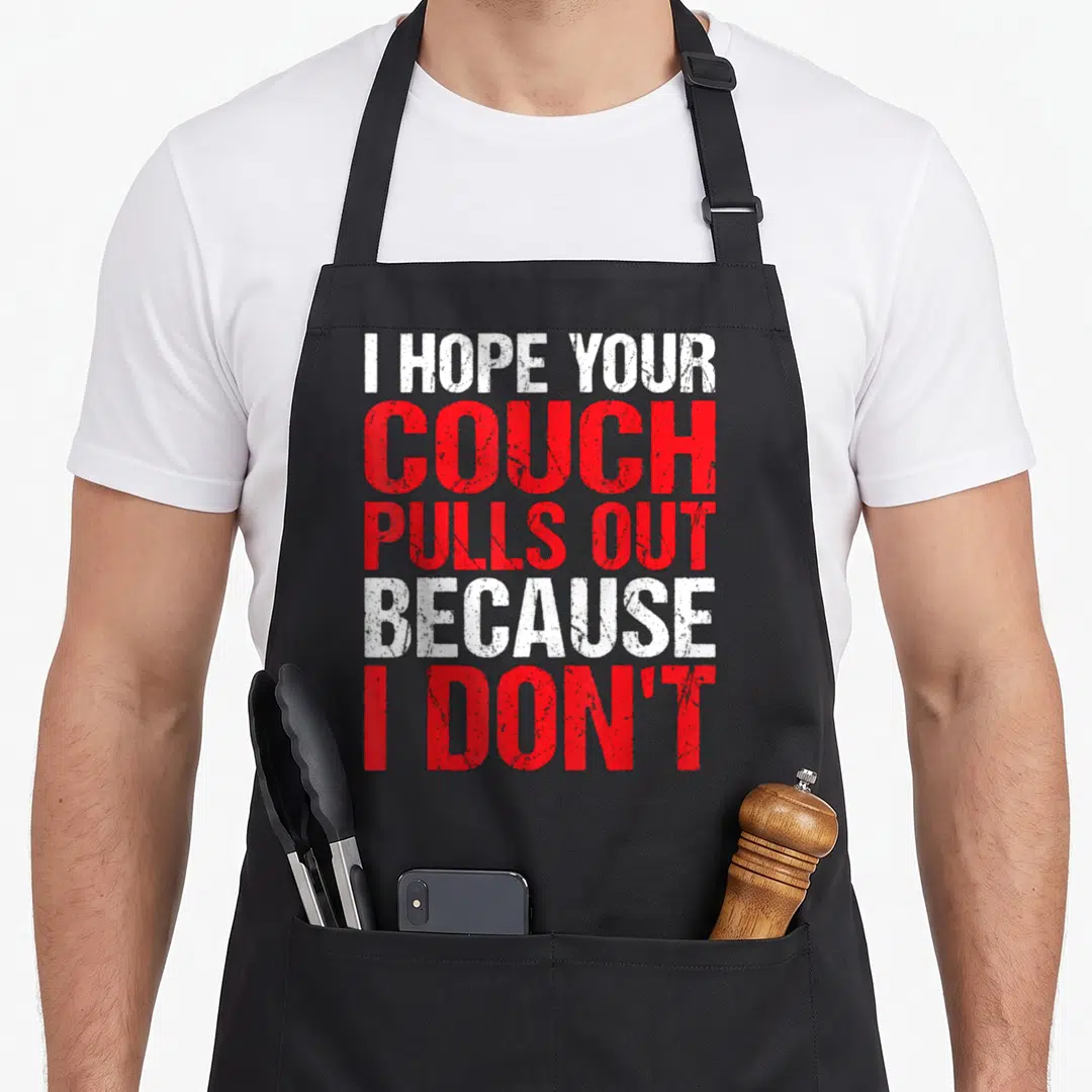 Pull vulgar aprons - Red and white stacked text reading I hope your couch pulls out because I don't — shown on a black cotton canvas apron against a white background