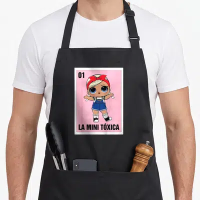 Funny game bingo aprons - Number 01 and cartoon girl on pink with La Mini Toxica text — shown on a black cotton canvas apron against a white background