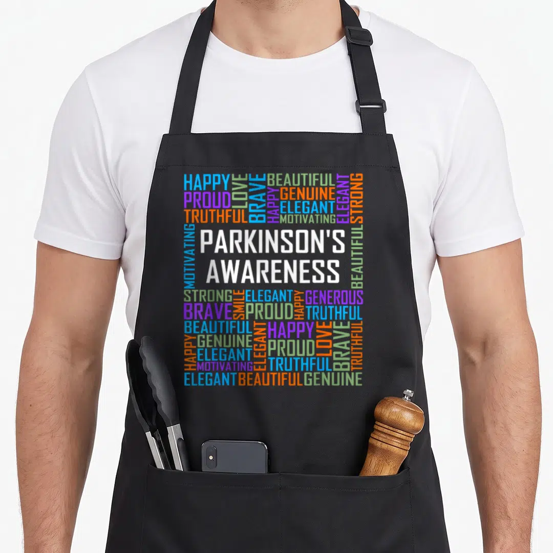 Fighter parkinsons awareness apron - Typography word cloud with white, blue, green, orange, and purple words — shown on a black cotton canvas apron against a white background