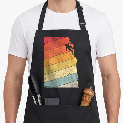 Rock climbing bouldering addict apron - Grey climber silhouette on diagonal red orange yellow beige blue and grey — shown on a black cotton canvas apron against a white background