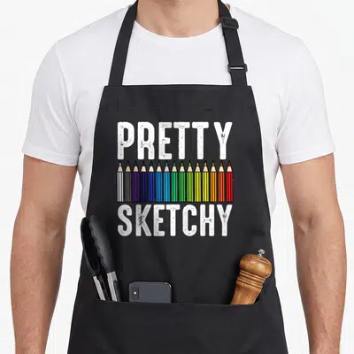 Pretty painter apron - Row of colored pencils between distressed white text reading pretty sketchy — shown on a black cotton canvas apron against a white background