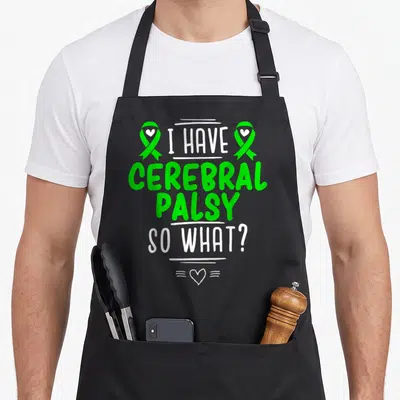 Survivor cerebral palsy awareness apron - Green and white I HAVE CEREBRAL PALSY SO WHAT text with two ribbons — shown on a black cotton canvas apron against a white background