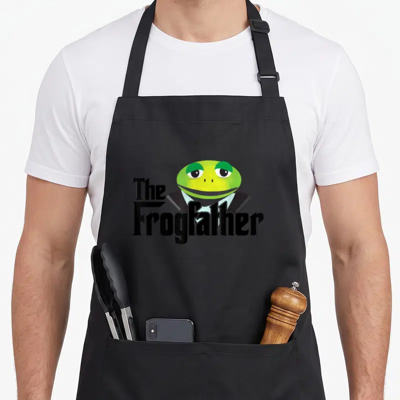 Frogfather frog aprons - Cartoon green frog in black suit with The Frogfather text — shown on a black cotton canvas apron against a white background