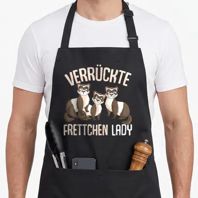 Crazy ferret gal apron - Three cartoon ferrets with VERRÜCKTE FRETTCHEN LADY text in beige and brown — shown on a black cotton canvas apron against a white background