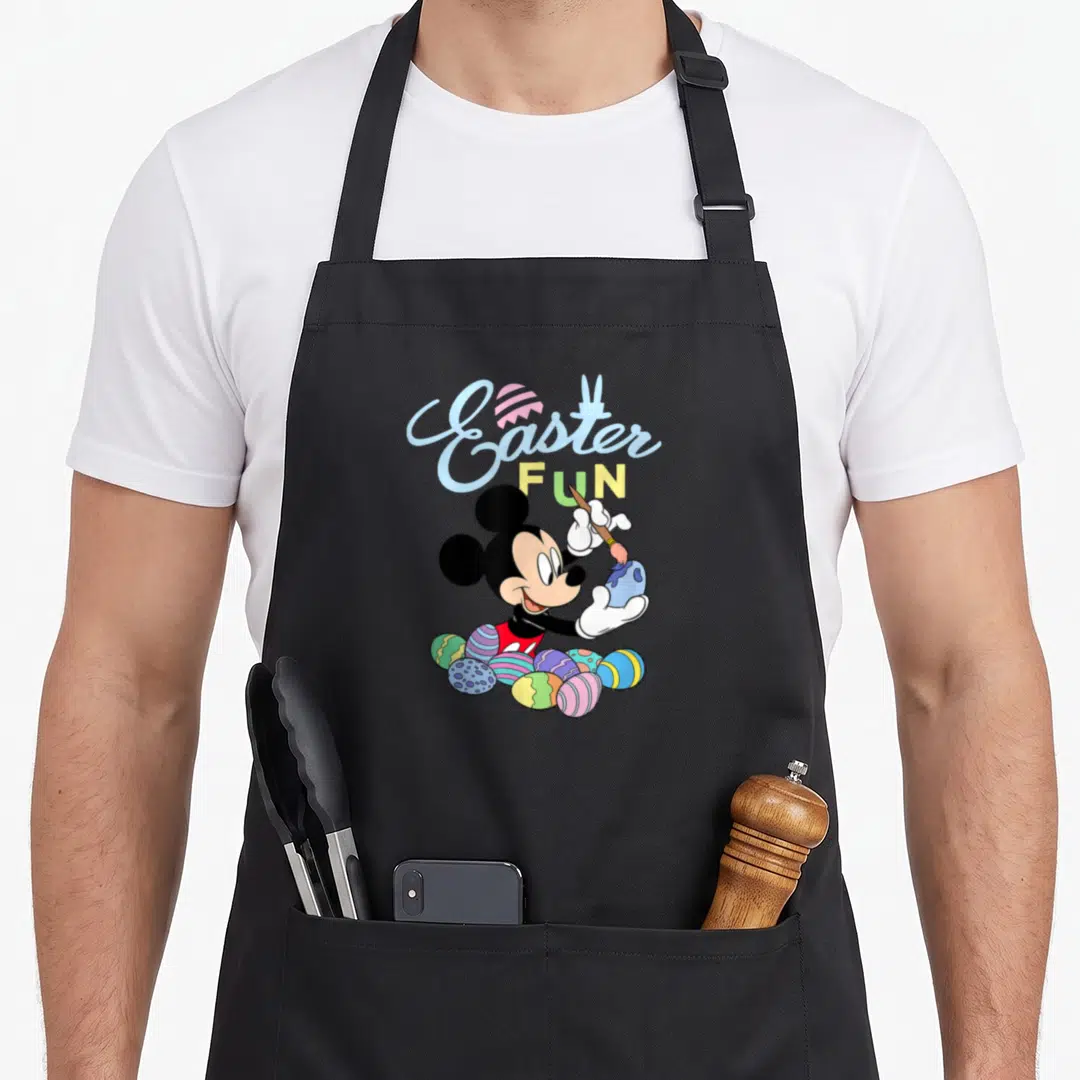Painting easter egg apron - Mickey Mouse painting a blue egg with Easter FUN text and colorful eggs at feet — shown on a black cotton canvas apron against a white background