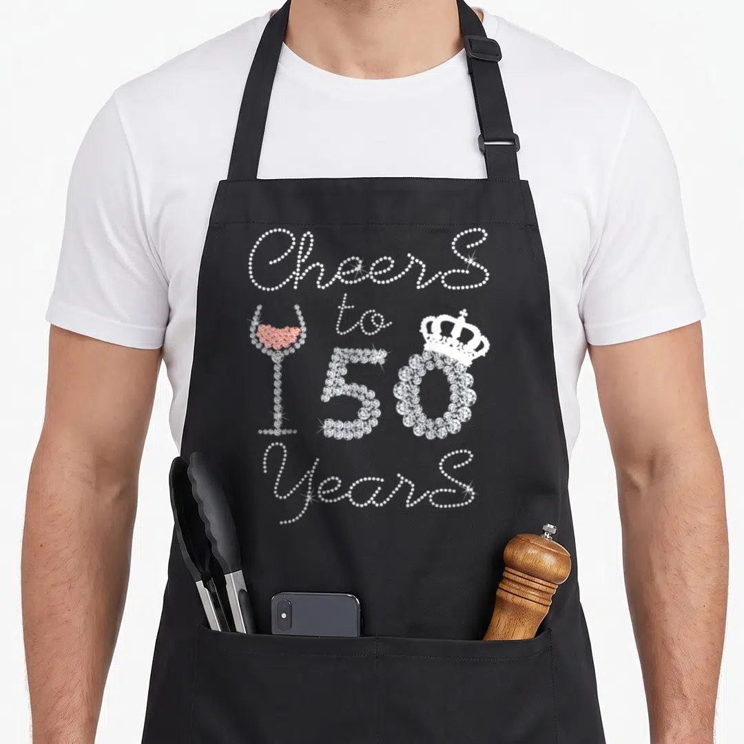 Queen wine apron - Stacked text Cheers to 150 Years with rhinestone style crown and red wine glass — shown on a black cotton canvas apron against a white background