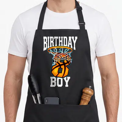 8th basketball birthday apron - Cartoon basketball hoop with ball forming number 8 and BIRTHDAY BOY text in orange — shown on a black cotton canvas apron against a white background