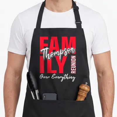 Thompson gathering apron - Red FAMILY text with white Thompson script and vertical REUNION Over Everything lettering — shown on a black cotton canvas apron against a white background