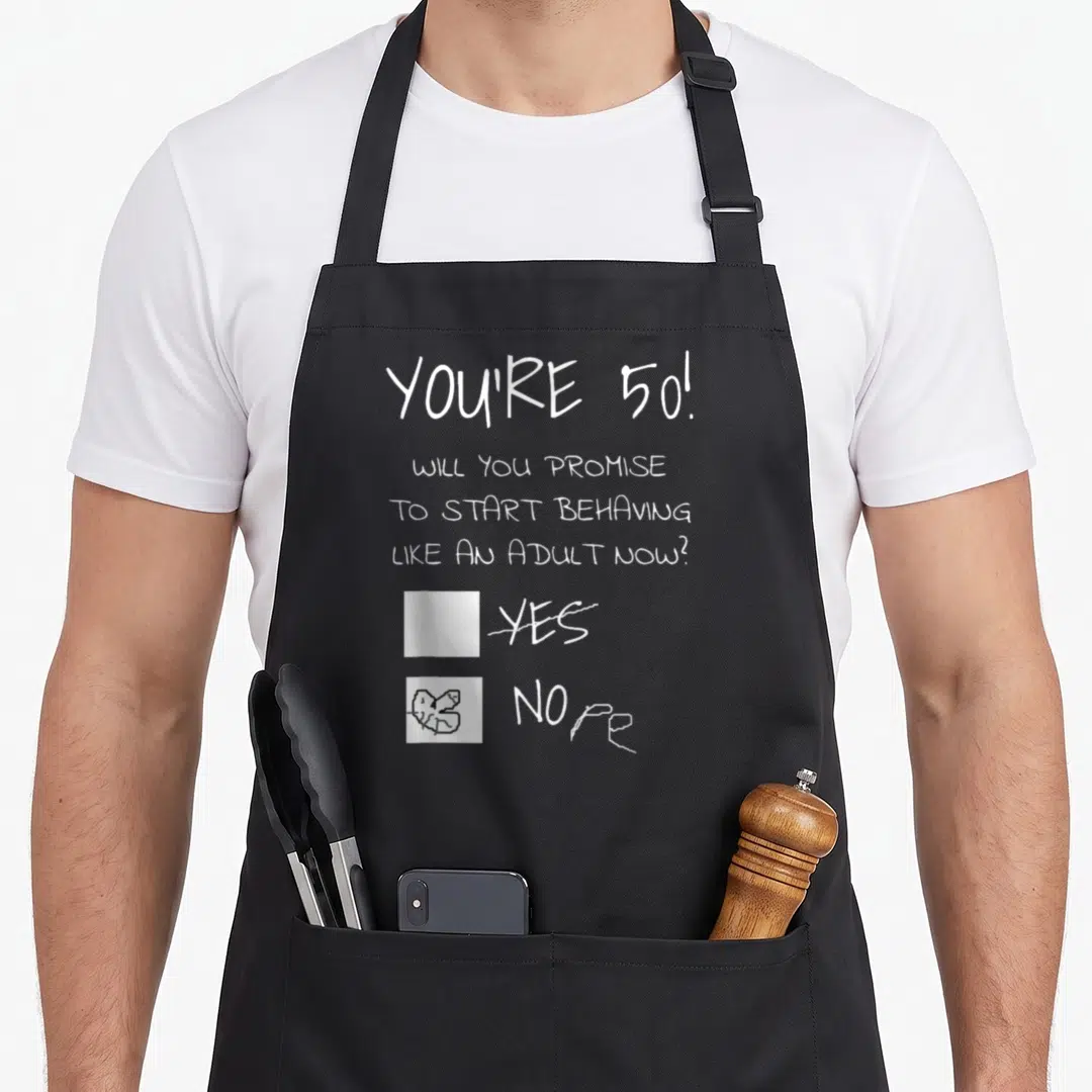 Present joke apron - White text asking about adult behavior with NOPE checkbox scribbled and YES crossed out — shown on a black cotton canvas apron against a white background