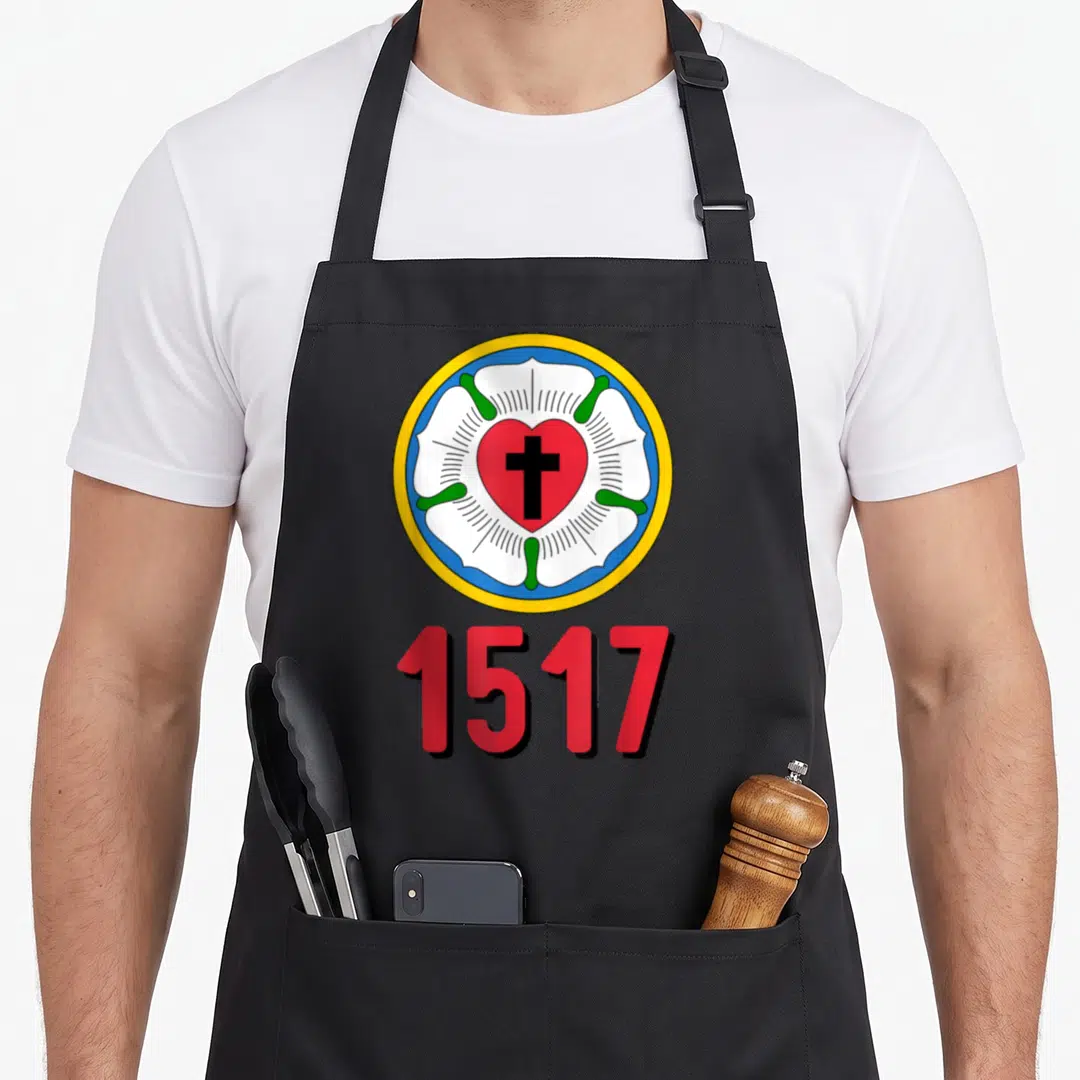 Lutheran protestant rose apron - Circular Luther Rose emblem with red heart black cross and 1517 text — shown on a black cotton canvas apron against a white background